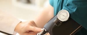 Female doctor measuring blood pressure of male patient in hospital