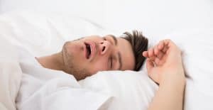 View Of Tired Young Man Snoring While Deep Sleeping In Bed