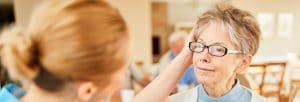 Caring caregiver comforts elderly woman with dementia or depression in retirement home